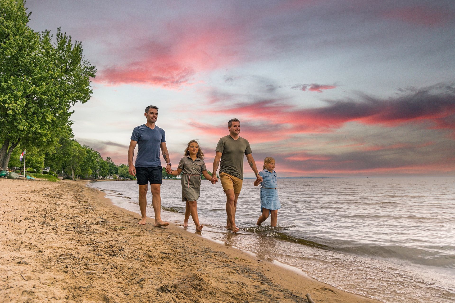 A family walks along a beach in North Bay at sunset