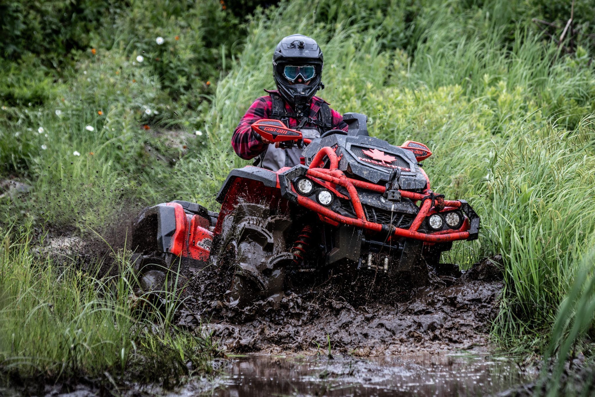 A person rides an ATV through the mud on the Voyageur Multi-Use Trail System
